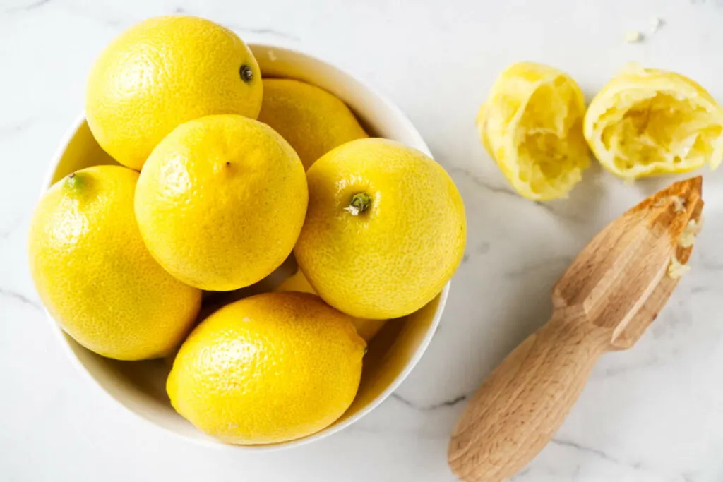 A bowl of lemons next to a lemon juicer.