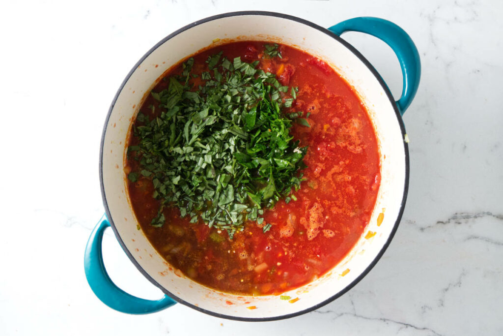 Adding fresh basil to tomato soup.