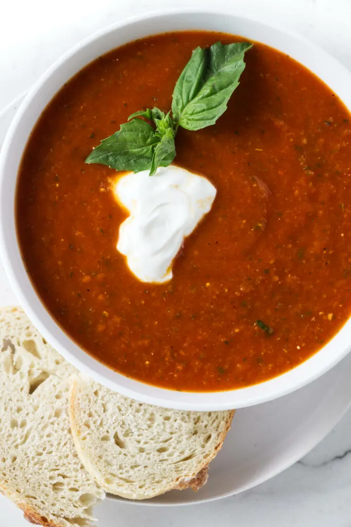 A bowl of tomato soup with a dollop of sour cream on top.