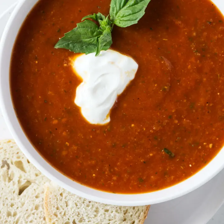 A bowl of tomato soup with a dollop of sour cream on top.