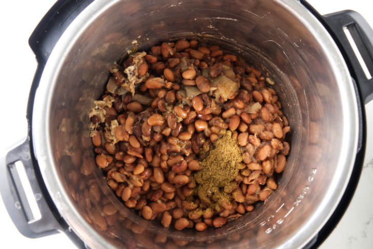 Cooked pinto beans in an Instant Pot with spices.