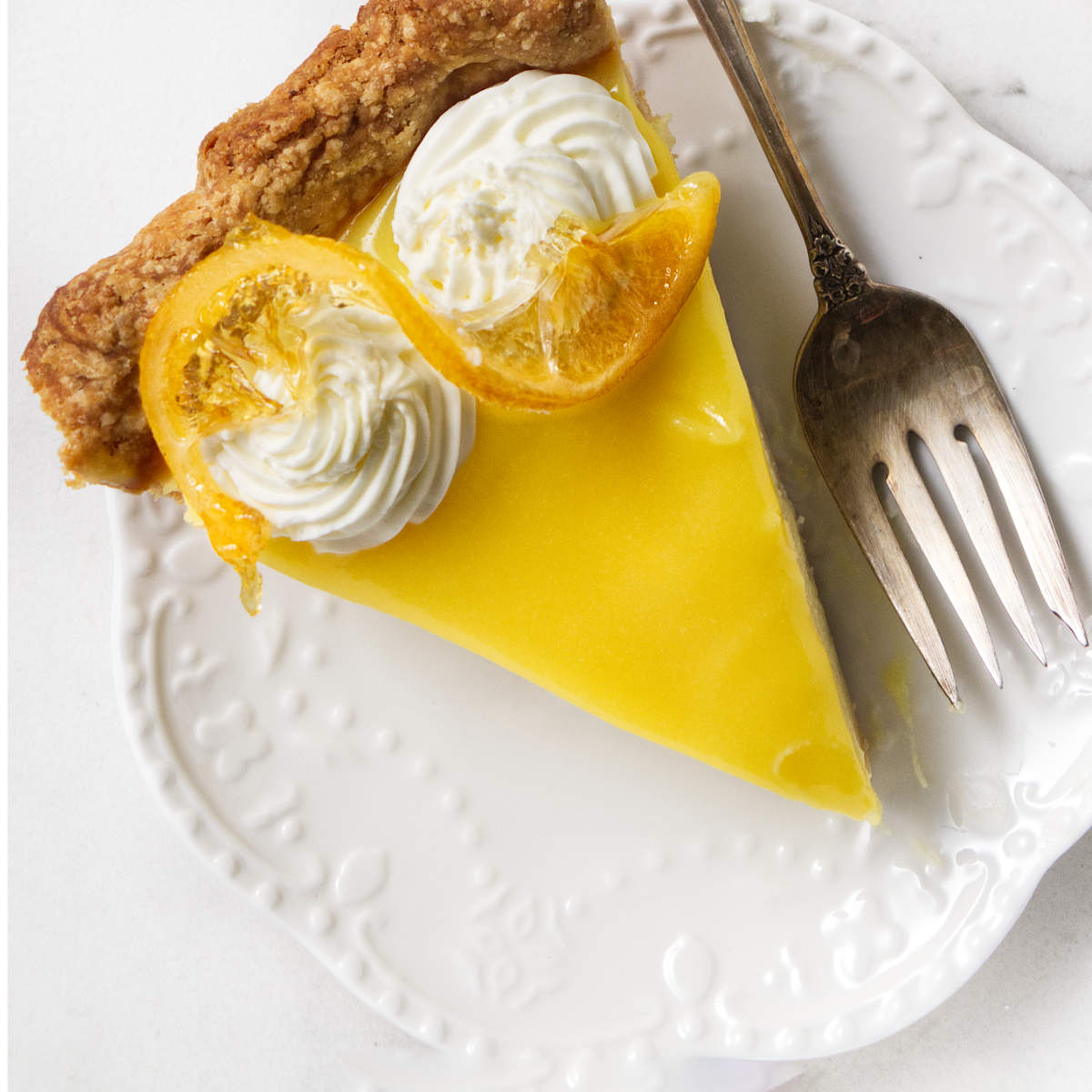 A slice of lemon custard pie topped with candied lemon slices.
