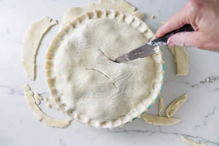 Cutting vent holes in the top of a pie.