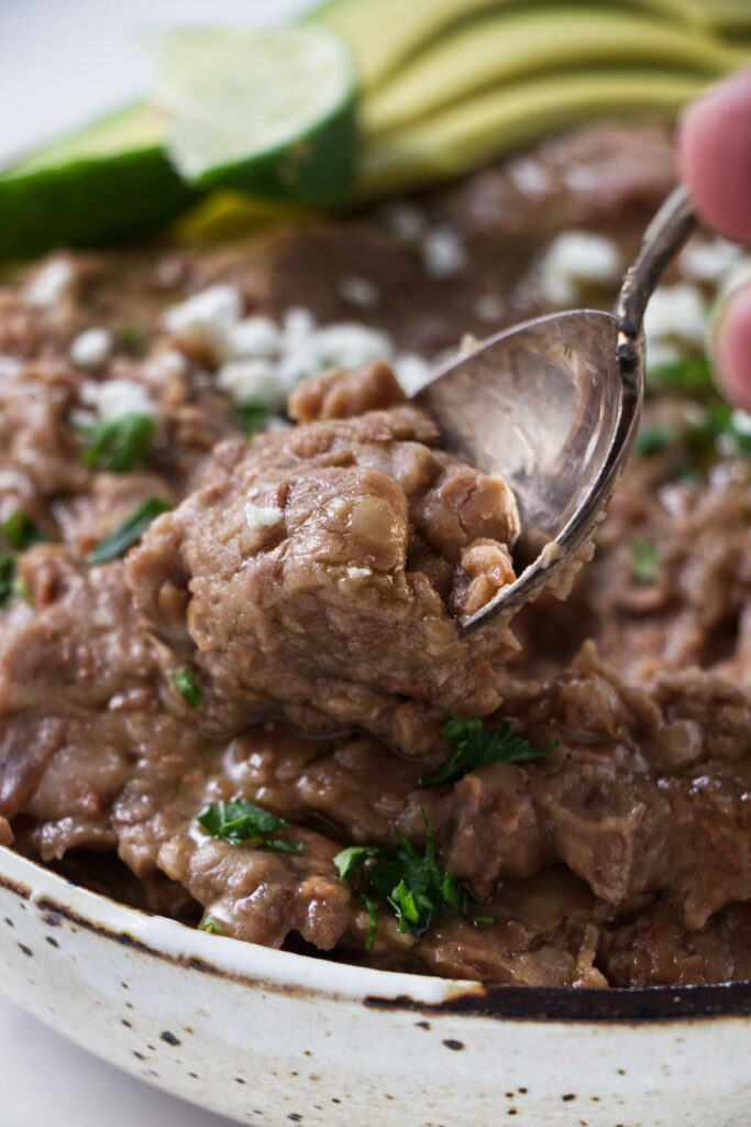 A spoon scooping up some freshly made refried beans.