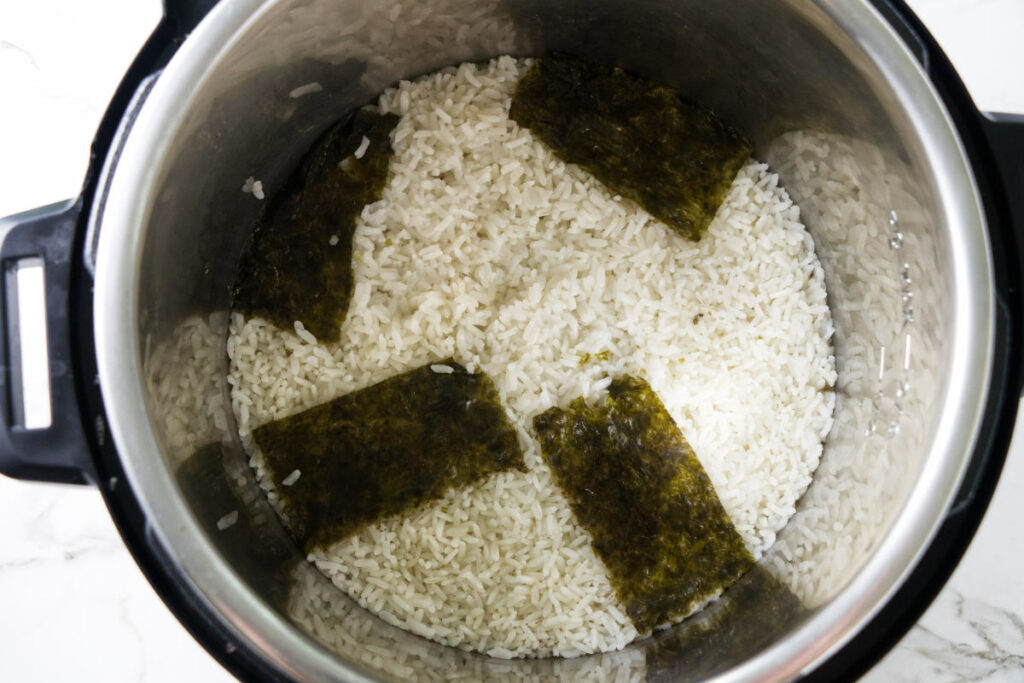 Freshly cooked sushi rice in an Instant Pot with dried seaweed.