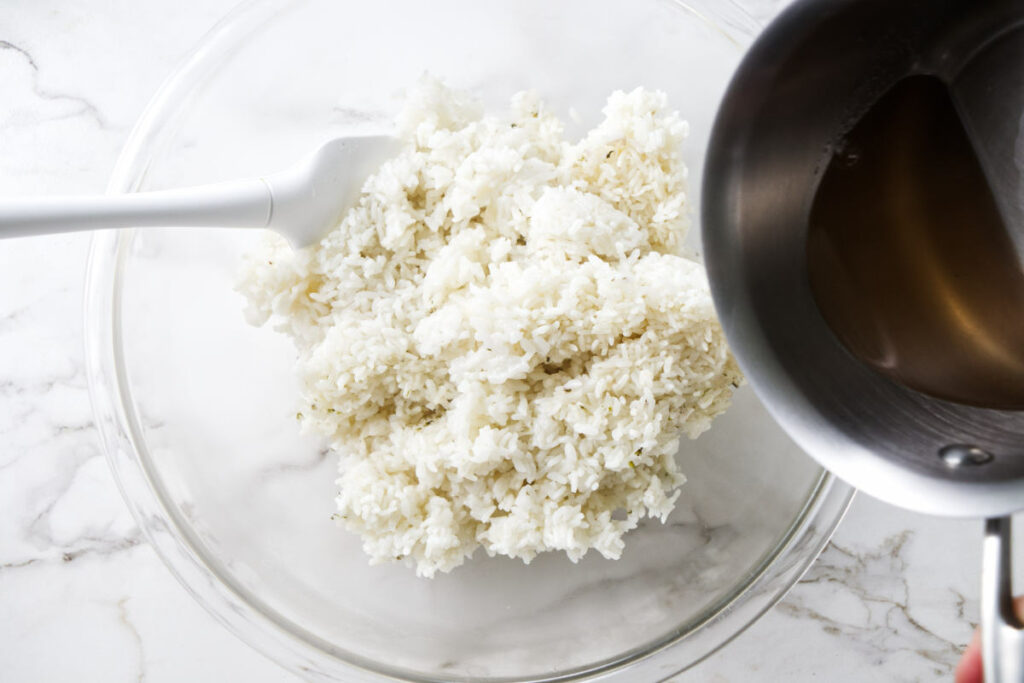 Pouring seasoned vinegar over sushi rice.