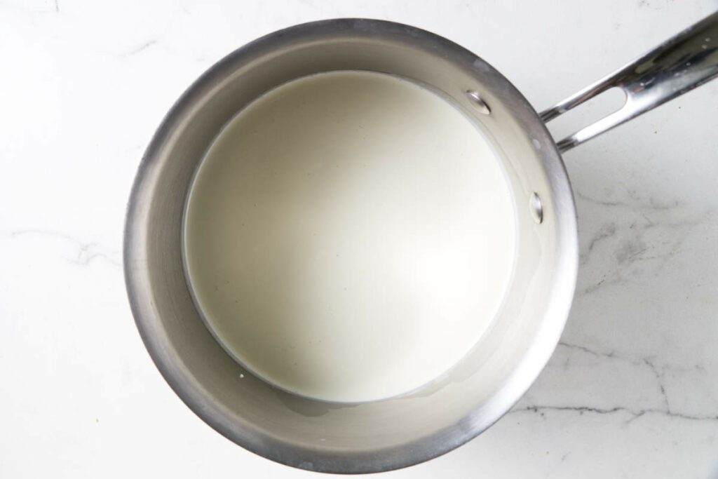 Heating milk and cream in a saucepan.