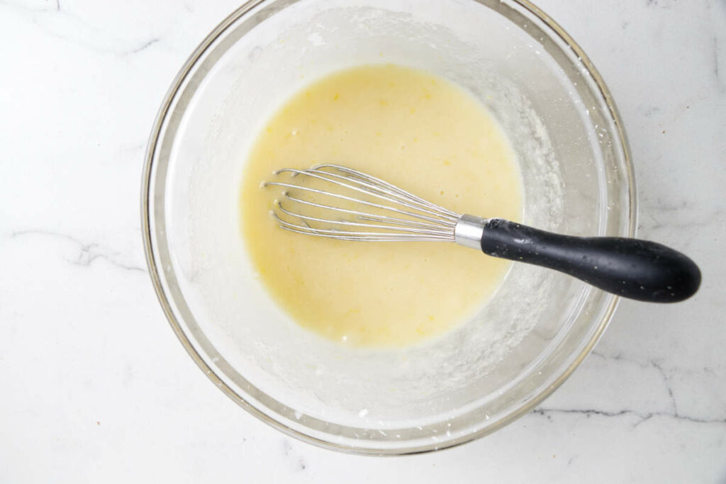 Whisking eggs with sugar, cornstarch, lemon juice, and flavorings.