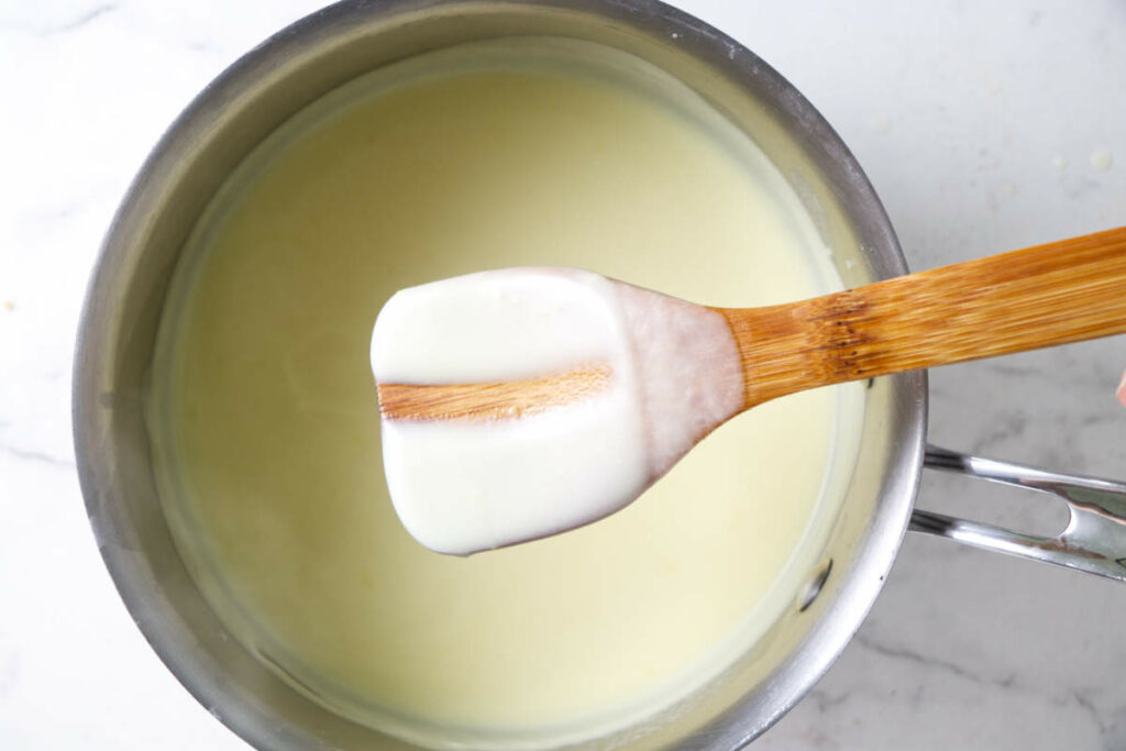 Showing how thickened custard will coat the back of a spoon and leave a track when you swipe a finger through it.