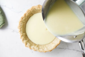 Pouring lemon custard into a pie shell.