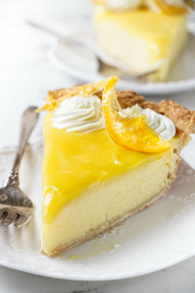 A slice of creamy lemon pie topped with lemon curd and candied lemon.