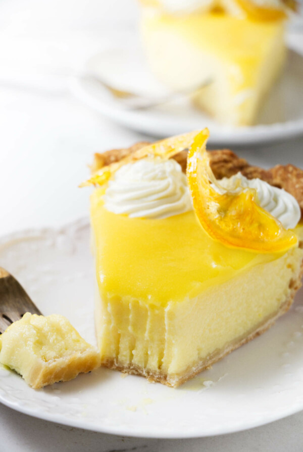 A partially eaten lemon pie next to a fork.