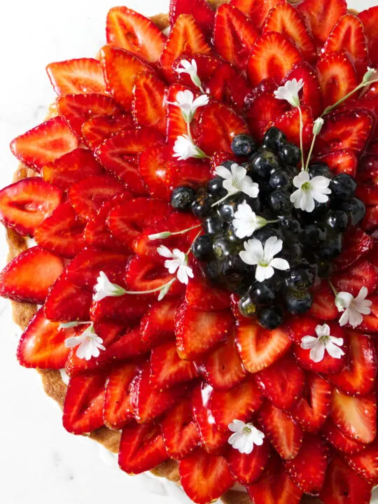 Sliced strawberries arranged in a star-like flower pattern on a tart.