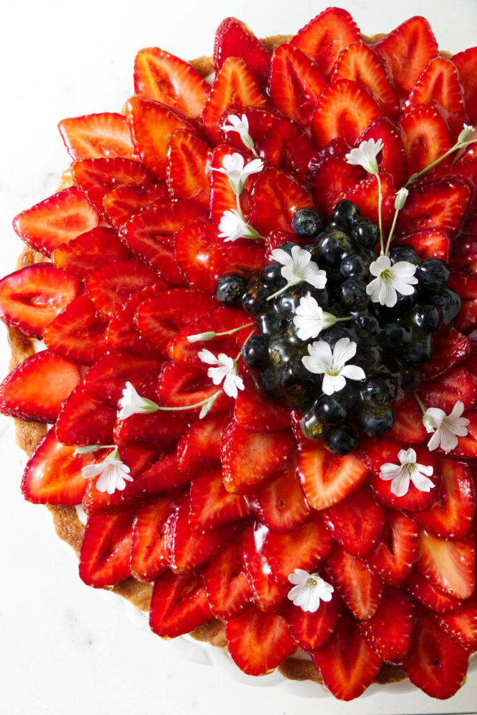 Sliced strawberries arranged in a star-like flower pattern on a tart.