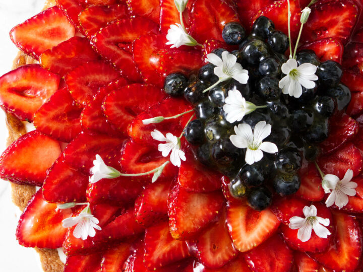 Sliced strawberries arranged in a star-like flower pattern on a tart.