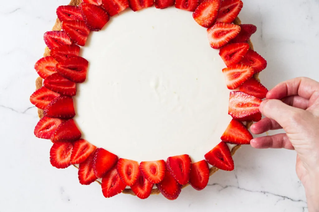 Arranging strawberry slices on a tart.