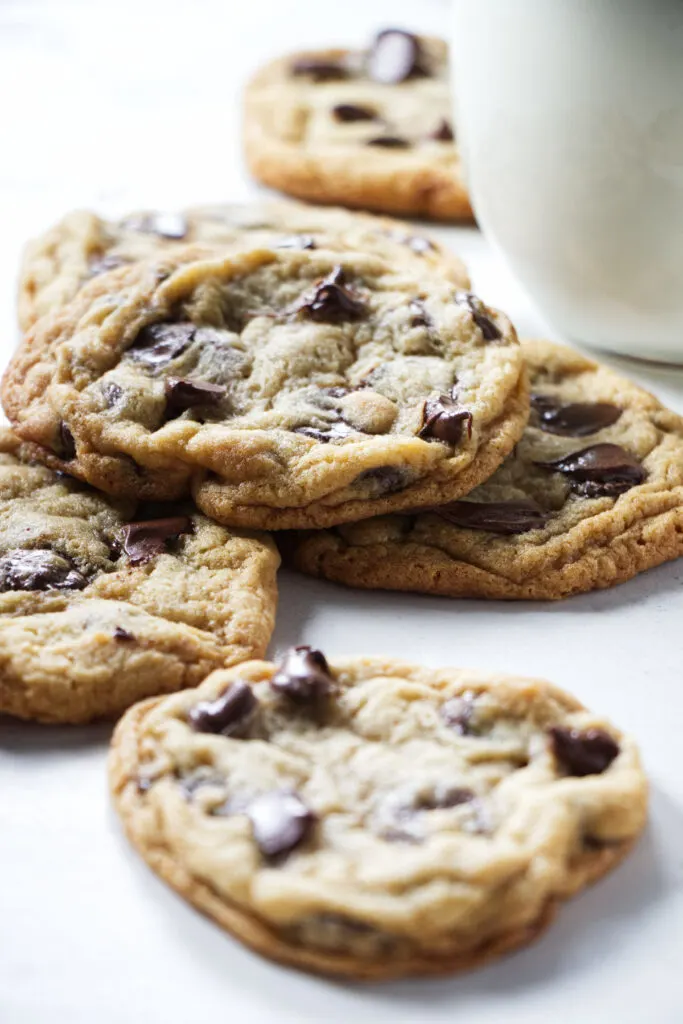 A pile of cookies next to a glass of milk.