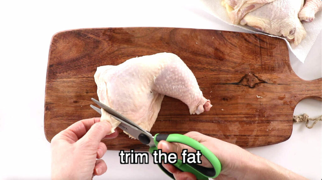 Trimming fat off a chicken quarter leg.