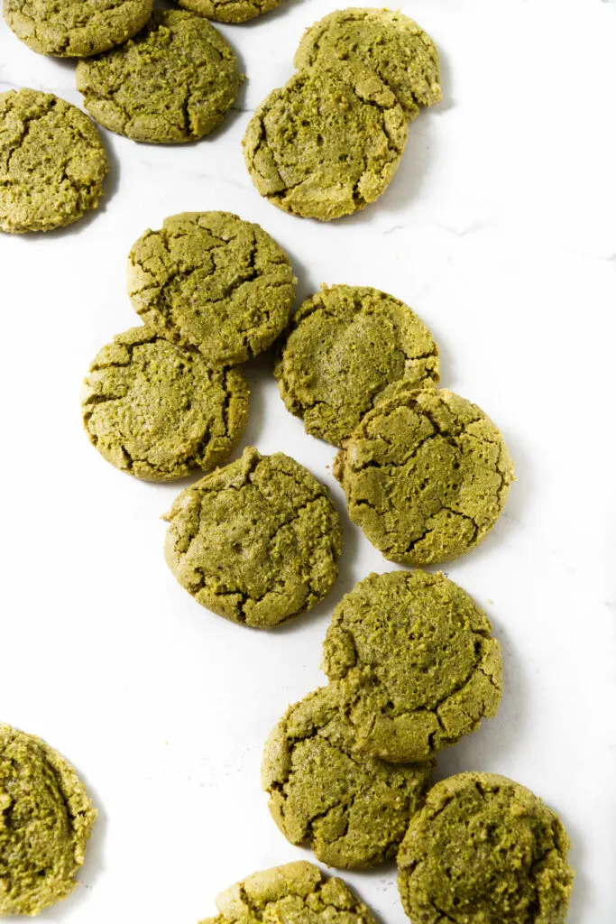 Several pistachio cookies scattered on a counter.