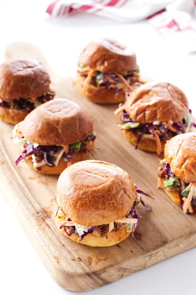 Cutting board with 6 pulled pork sliders.
