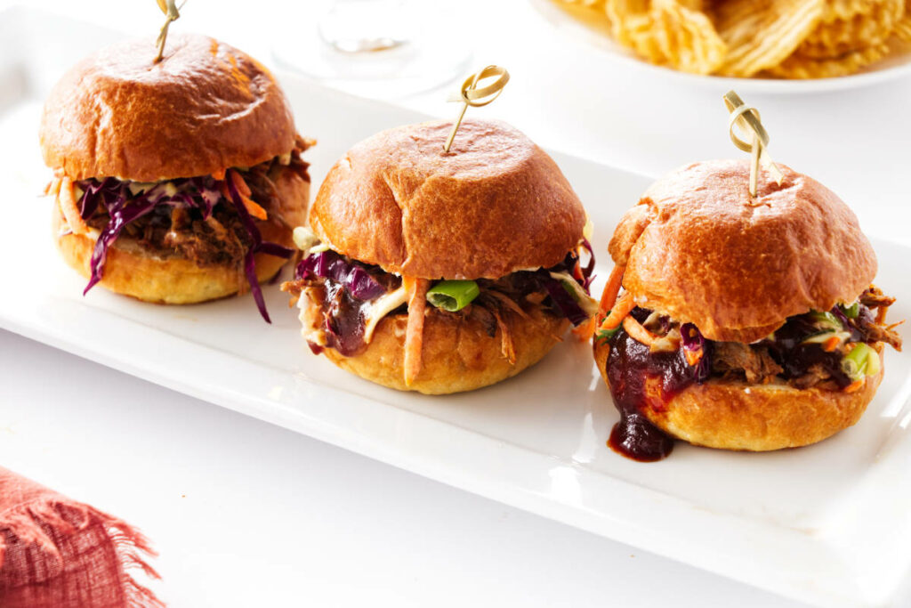 Close up of 3 pulled pork sliders on a plate.