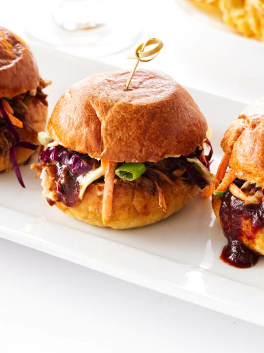 Close up of 3 pulled pork sliders on a plate