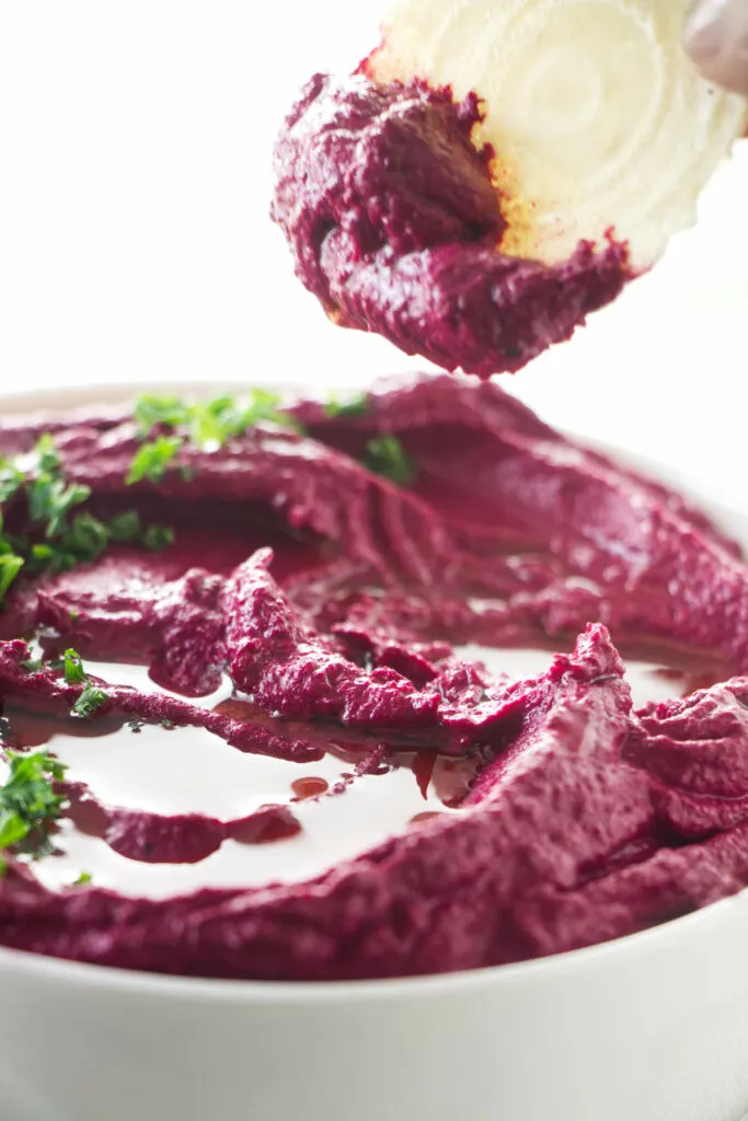 Dipping a cracker in beet hummus.