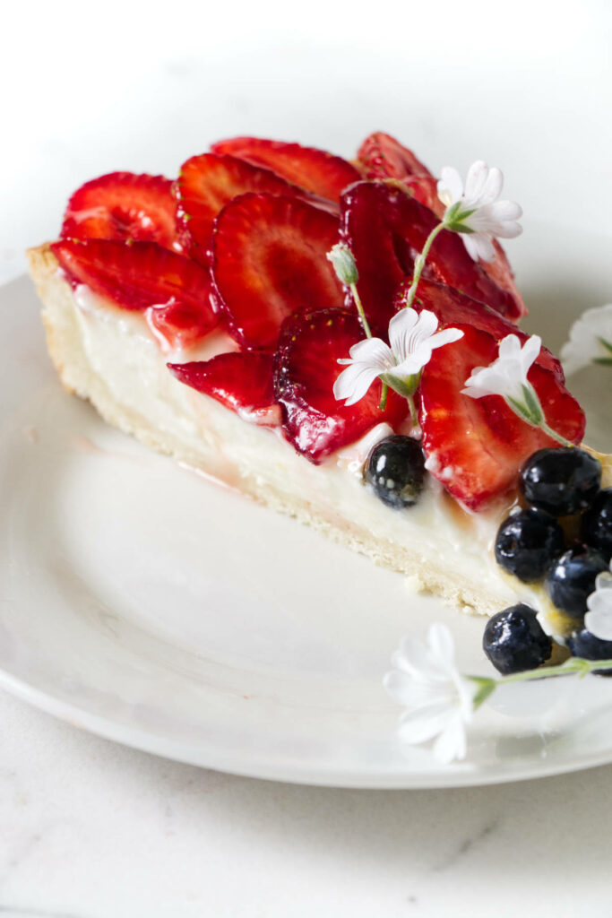 A slice of fruit tart showing the red, white, and blue colors from the fruit and cream filling.