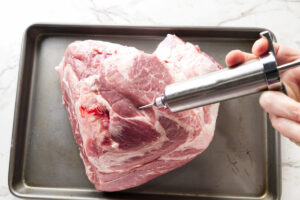 Injecting a pork shoulder with marinade.