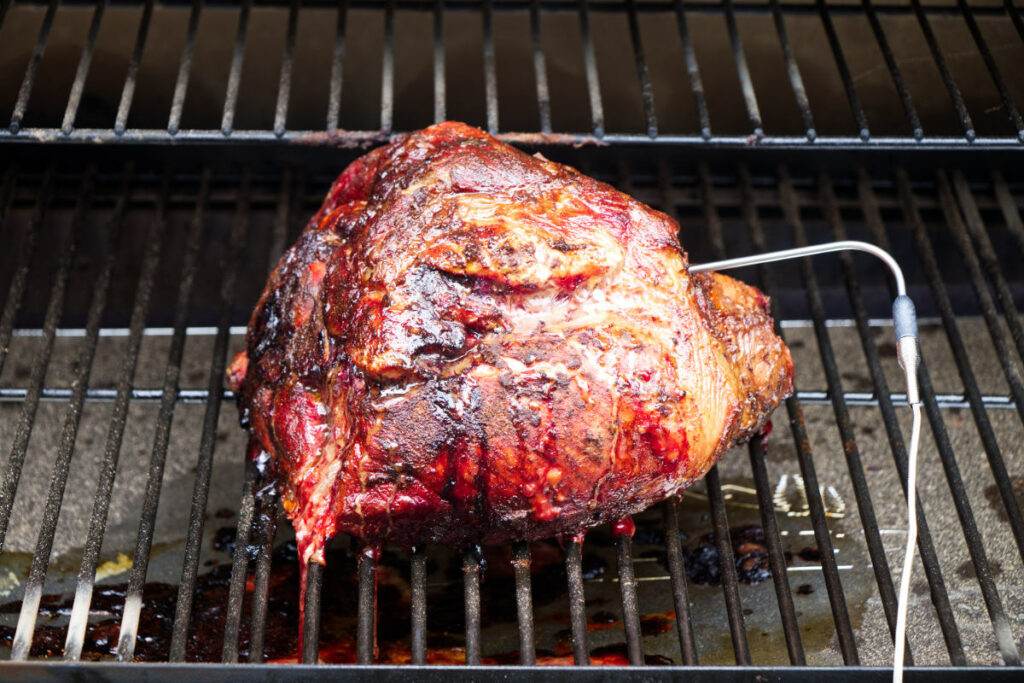 Smoking pork shoulder on a grill.