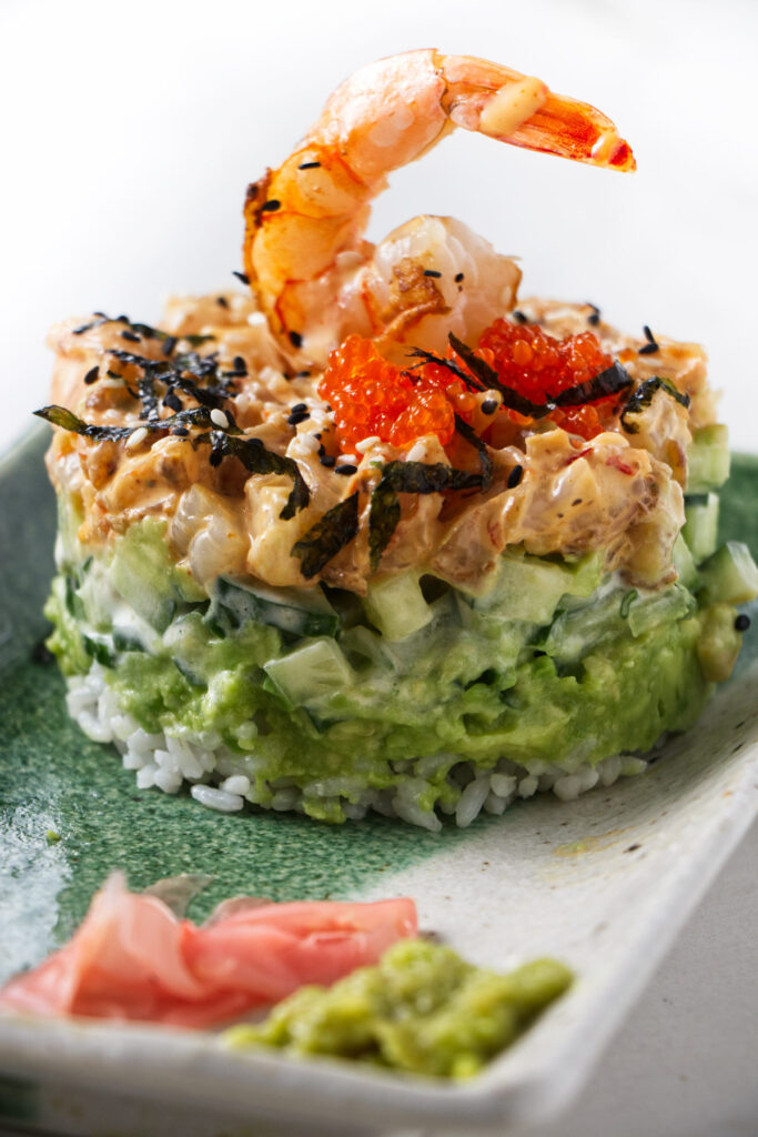 A shrimp stack on a sushi plate with wasabi and ginger.