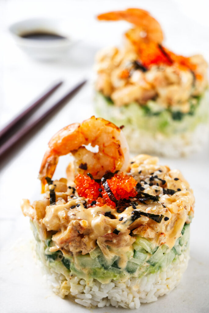 Two shrimp sushi stacks with chopsticks and soy sauce.