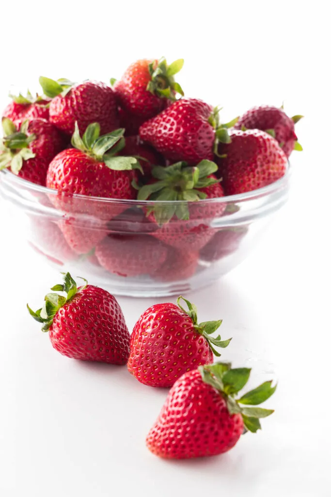 A dish of fresh strawberries with three in the foreground