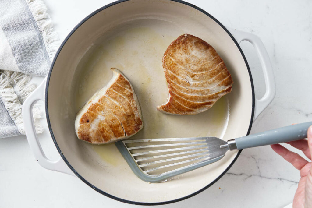 Cooking tuna steaks in a skillet.