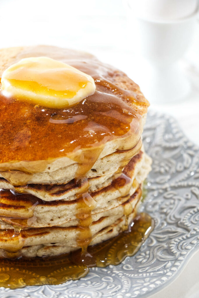 Butter and syrup on a stack of barley pancakes.