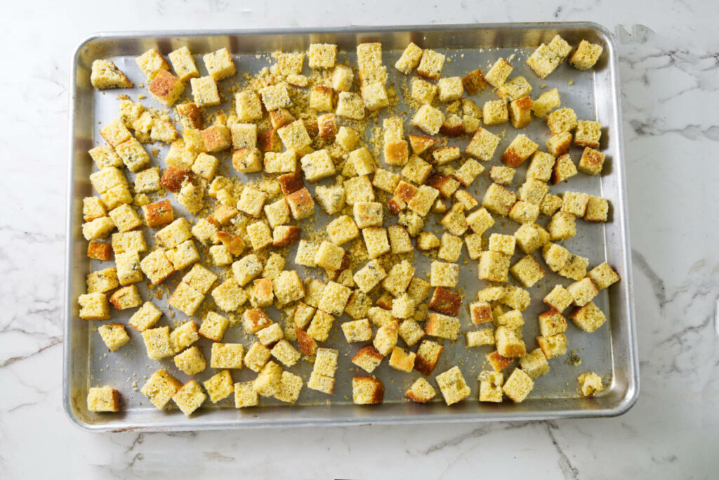 Cubes of cornbread on a baking tray.