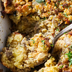 A spoon scooping stuffing out of a casserole dish.