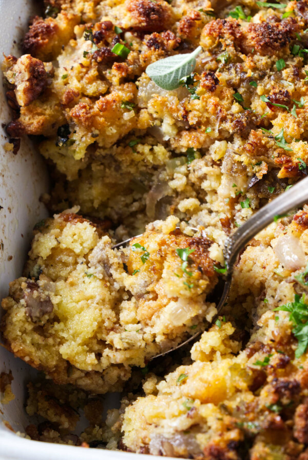 A spoon scooping stuffing out of a casserole dish.