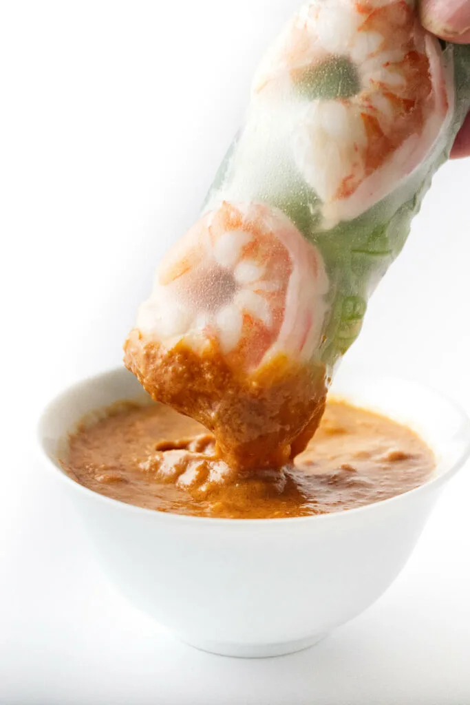 Dipping a shrimp spring roll in peanut sauce.