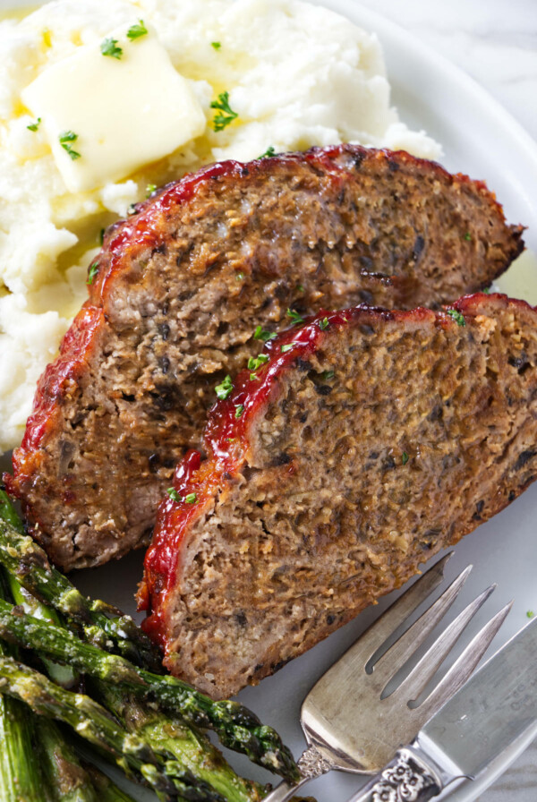 Two slices of turkey meatloaf on a plate with mashed potatoes.