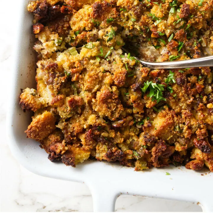 Scooping cornbread stuffing out of a casserole dish.