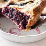 Close up of a slice of pie being lifted with a pie server.