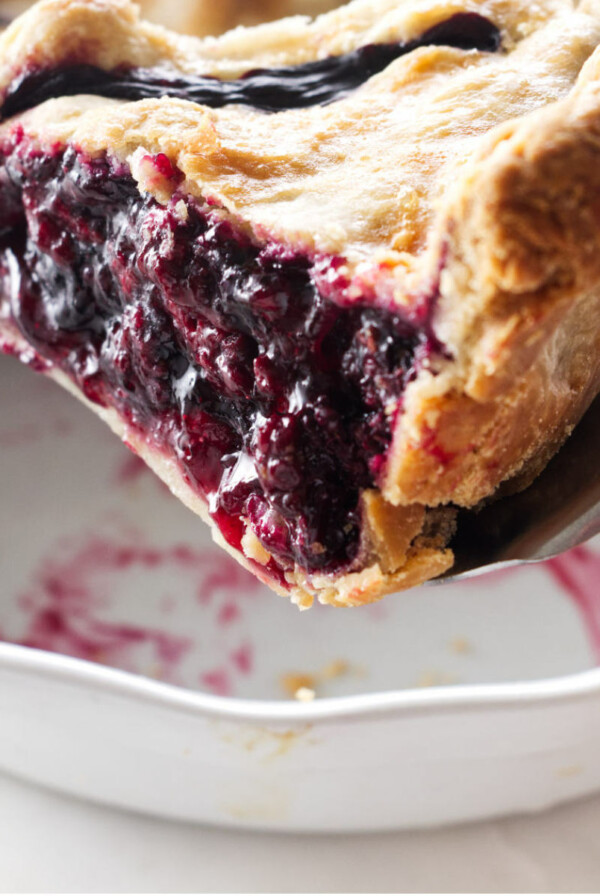 Close up of a slice of pie being lifted with a pie server.