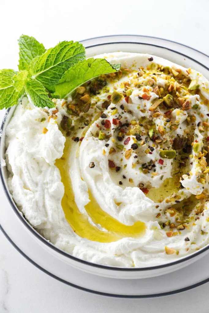 A dish of labneh with za'atar spice, olive oil, and mint.