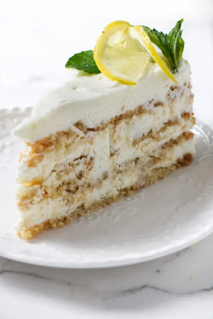 A slice of lemon cake garnished with lemon and mint.