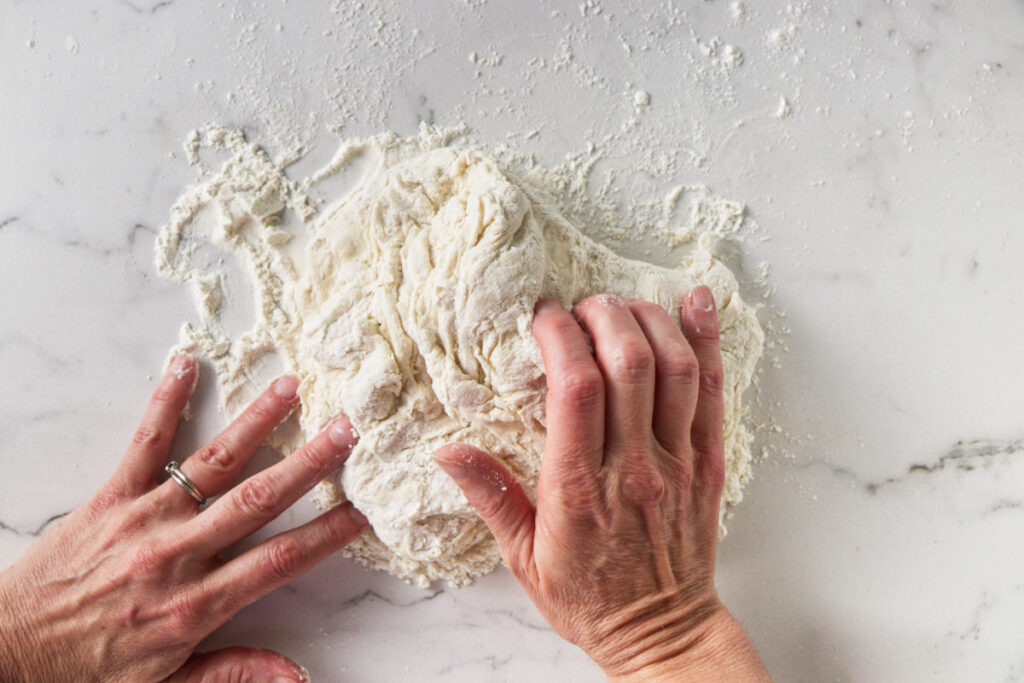 Kneading pizza dough on a counter.
