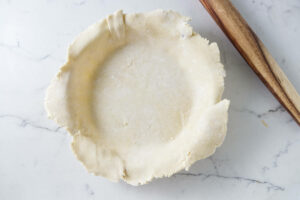 A pie crust in the bottom of a pie dish.