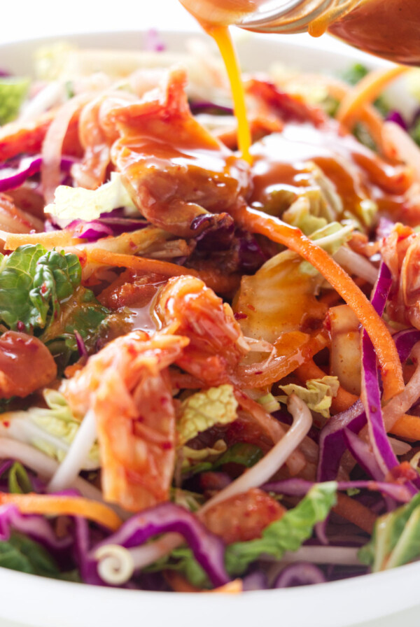 Pouring vinaigrette over a slaw salad.