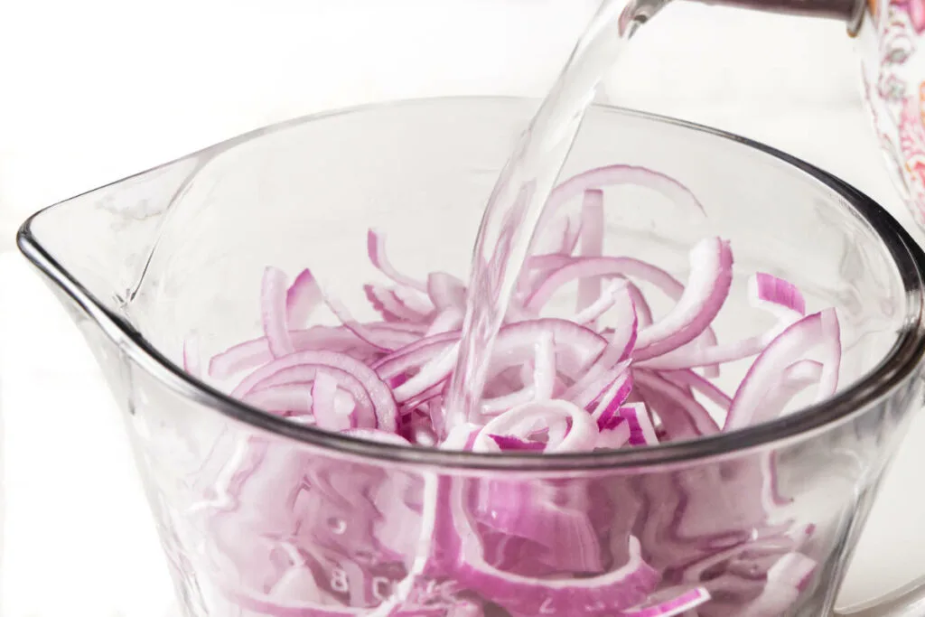 Pouring hot water over red onions.