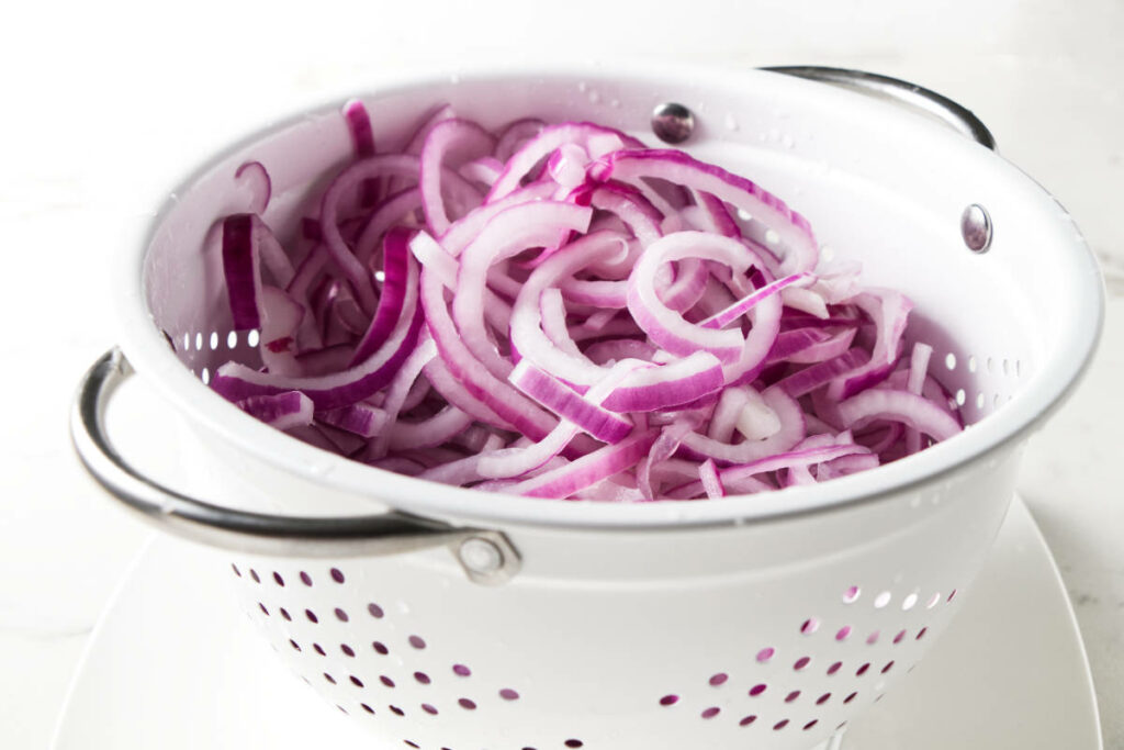 Draining onion slices in a colander.